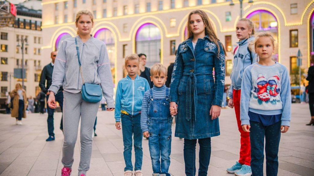 a group of children stands in the crowd on the street